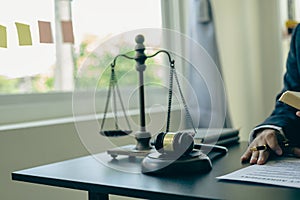 Law and Justice Lawyer working with documents and laptop, hammer, scale at wooden table in office Close-up