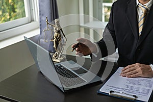 Law and Justice Lawyer working with documents and laptop, hammer, scale at wooden table in office Close-up