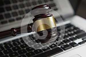 Law legal concept photo of gavel on computer with legal books in background.