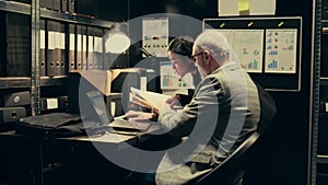 Law officers reading confidential folders in archive room at private company