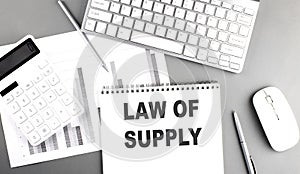 LAW OF SUPPLY text on notebook with calculator , chart and keyboard business concept