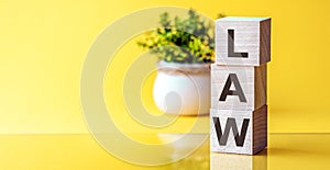 LAW Word On Wooden Blocks on table with flowers on yellow background. Law and Justice, Legality concep