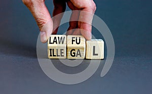 Lawful or illegal symbol. Concept word Lawful or Illegal on wooden cubes. Beautiful grey table grey background. Businessman hand.