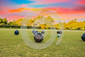 Lawn bowls balls in a field after the game with a colourful sunset