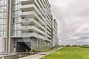 lawn covered with grass near a new modern multi-storey residential building, fountains of water