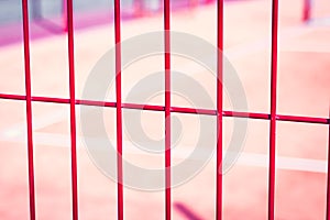 lawn field for playing basketball behind the orange fence mesh. Metal mesh wire with tennis court.