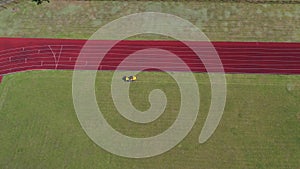 Lawn mower cutting grass from football soccer field, aerial