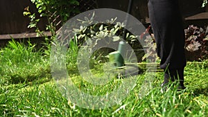 Lawn mower cutting grass. Small Green grass cuttings fly out of lawnmower pushed around by landscaper. Close Up Gardener