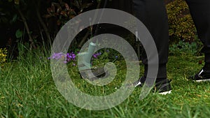 Lawn mower cutting grass. Small Green grass cuttings fly out of lawnmower pushed around by landscaper. Close Up Gardener