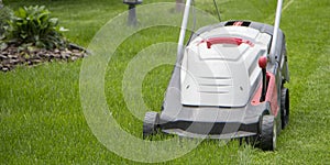 Lawn mower cutting green grass in backyard