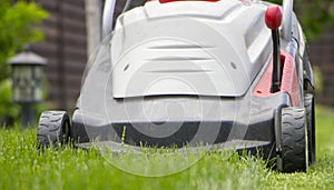 Lawn mower cutting green grass in backyard