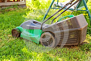 Lawn mower cutting green grass in backyard