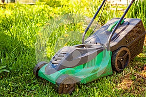 Lawn mower cutting green grass in backyard