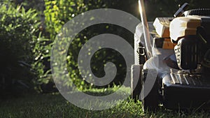 Lawn mower cutting green grass in backyard