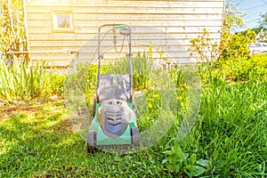 Lawn mower cutting green grass in backyard