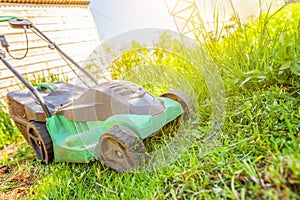 Lawn mower cutting green grass in backyard