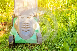 Lawn mower cutting green grass in backyard