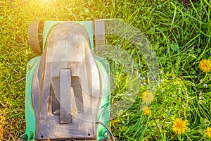 Lawn mower cutting green grass in backyard