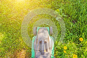 Lawn mower cutting green grass in backyard