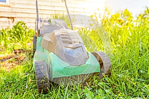 Lawn mower cutting green grass in backyard