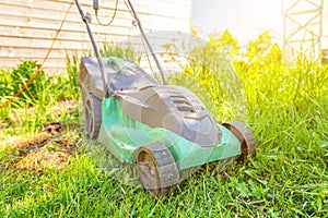 Lawn mower cutting green grass in backyard