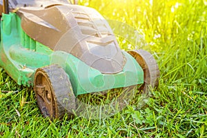 Lawn mower cutting green grass in backyard