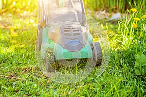 Lawn mower cutting green grass in backyard