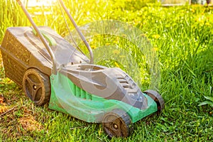 Lawn mower cutting green grass in backyard