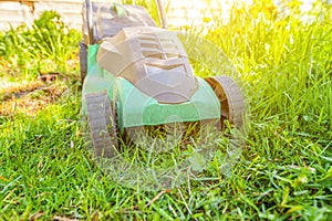 Lawn mower cutting green grass in backyard