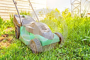 Lawn mower cutting green grass in backyard