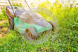 Lawn mower cutting green grass in backyard