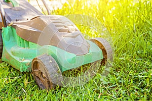 Lawn mower cutting green grass in backyard