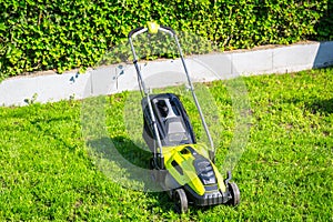 Lawn mower cutting green grass in backyard