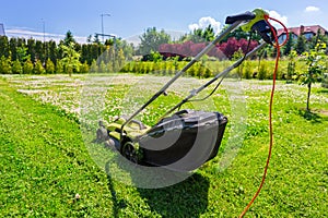 Lawn mower cutting green grass in backyard