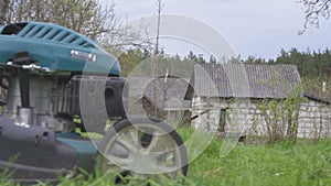 Lawn mower cutting green grass in backyard. Gardening background.