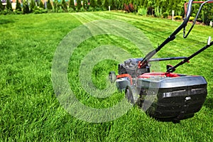 Lawn mower cutting green grass in backyard