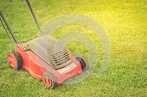 Lawn mower cutting green grass/red lawn mower on a green lawn