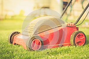 Lawn mower on the grass in the yard against sunshine/lawn mower on the grass in the yard against sunshine. Selective focus