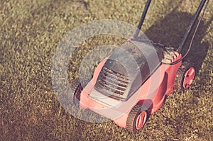 Lawn mower on the lawn/red lawn mower on summer meadow. Toned and copyspace