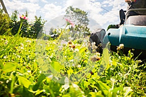 Lawn mower in motion on green grass in garden or backyard. Machine for cutting lawns. Gardening care tools and equipment