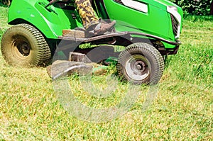 Lawn mower rides on the lawn and mows the grass. Mowing the lawn in the park