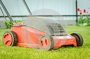 Lawn mower on the tonsured lawn/red lawn mower on the tonsured lawn. Selective focus