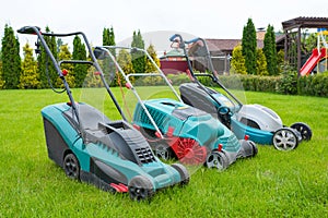 . Lawn mowers are standing on the lawn in the garden backyard. A close-up of an electric lawn mower