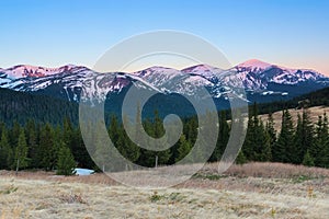 From the lawn opens a panoramic view of the mountains with snow covered picks, illuminated by the morning sun rays.