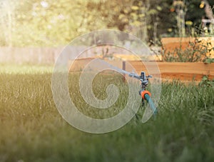 Lawn sprinkler in green grass pouring water drops and splashes