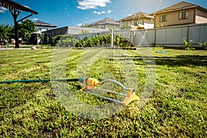 Lawn sprinkler spaying water over green grass. Irrigation system