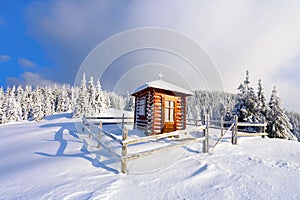 On the lawn there is wooden church covered with snow high on the mountains.