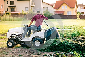 Lawn tractor unloading cut grass during landscaping works