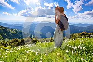 On the lawn of white daffodils flowers the hipster girl with back sack stays enjoying the sunset. Morning lights.