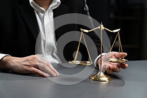 Lawyer in black suit with golden scale balance in office. equility